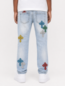 Light wash blue denim jeans with multiple colorful embroidered cross patches in blue, green, yellow, silver, and red, shown on a model from the back against a white studio background.