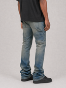 A person shown from the back wearing light-wash blue distressed jeans with a black t-shirt and black shoes, standing against a light gray studio background.