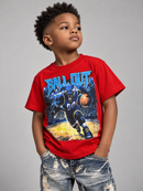 A young boy wearing a bright red graphic t-shirt with a basketball player print and the words 'BALL OUT' in blue, paired with distressed blue jeans, standing against a solid gray studio background.