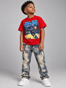 A young boy modeling a red graphic t-shirt with a basketball player print, paired with distressed blue jeans and white sneakers, standing against a neutral gray studio background.