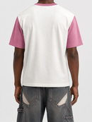 A person shown from the back wearing a short-sleeve ringer T-shirt with a white body and pink sleeves, paired with gray cargo-style jeans against a light gray studio background.