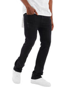 A person wearing slim black jeans with distressed details on the thighs, styled with a white t-shirt and white sneakers against a plain white background.