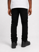 Rear view of a person wearing slim-fit black jeans with a white t-shirt and black shoes, photographed against a light gray studio background.