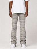 A person wearing light gray textured striped jeans with a unique layered, ribbed design, styled with a white t-shirt and white sneakers against a light gray studio background.