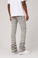 A person shown from the back wearing light gray textured denim jeans with horizontal stitched panel details, a white t-shirt, and white sneakers against a light gray studio background.