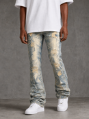 A person wearing distressed light-wash blue jeans with faded beige and gray areas, a loose white T-shirt, and white sneakers, standing against a textured gray studio background.