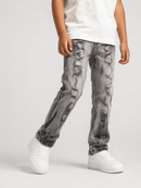 A child wearing distressed gray denim jeans with a faded wash, paired with a white t-shirt and white sneakers, shown from the waist down against a light gray studio background.