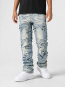 Light blue distressed denim jeans with heavy rips and frayed details, worn by a model with a black t-shirt and white sneakers against a light gray background.