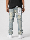 Rear view of a person wearing light-wash distressed jeans with ripped details, a black t-shirt, and white sneakers against a light gray studio background.