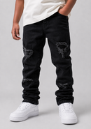 A person wearing black distressed jeans with ripped details on the thighs and lower legs, paired with a white t-shirt and white sneakers, shown from the waist down against a light gray studio background.