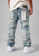 Back view of a person wearing light blue acid-wash denim jeans with white sneakers and a cream t-shirt, shown against a neutral gray studio background.