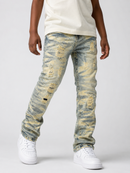 A child wearing distressed faded blue jeans with yellowish-tan abrasion patches, paired with a cream sleeveless top and white sneakers, shown against a light gray studio background.