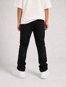 A person shown from the back wearing black distressed jeans, a white t-shirt, and white sneakers against a light gray studio background.