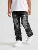 A child wearing distressed black and gray washed jeans, a white t-shirt, and white sneakers, shown from the waist down against a light gray studio background.