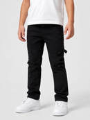 A person wearing black distressed cargo-style jeans with ripped details, paired with a white t-shirt and white sneakers, photographed against a light gray studio background.