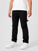A person wearing black distressed cargo-style jeans with ripped details on the thighs and knees, paired with a white t-shirt and white sneakers, photographed against a light gray studio background.