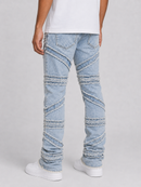 Light wash blue denim jeans with diagonal stitched paneling and frayed detailing, shown on a model from the back wearing a white t-shirt and white sneakers against a light gray studio background.