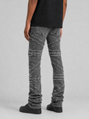 Rear view of a person wearing dark gray denim jeans with diagonal textured knit fabric panels, a black t-shirt, and black shoes against a light gray studio background.