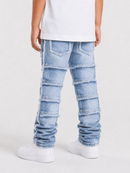 A child wearing light blue patchwork distressed jeans with layered frayed denim panels, shown from the back against a plain white studio background.