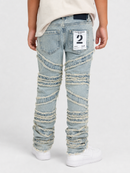 A person shown from the back wearing light-wash distressed denim jeans with horizontal frayed striping down the legs, a cream t-shirt, and white sneakers against a light gray studio background.