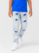 A child wearing light-wash distressed jeans with blue sequined ripped details, paired with a bright blue t-shirt and white sneakers, shown from the waist down on a light gray studio background.