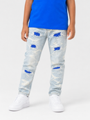 A child wearing light-wash distressed denim jeans with blue sequined tear details, paired with a bright blue t-shirt and white sneakers, shown from the waist down against a light gray studio background.