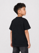 A young boy shown from the back wearing a black short-sleeve t-shirt with distressed details and dark gray jeans, photographed against a light gray studio background.