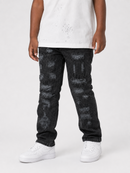 A child wearing black distressed denim jeans with a faded gray splatter pattern, styled with a white t-shirt and white sneakers against a light gray studio background.