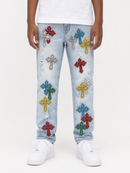 A person wearing light-wash blue jeans with multiple colorful embroidered cross patches in red, blue, yellow, green, and silver, paired with a white t-shirt and white sneakers against a plain white background.