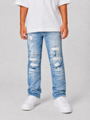 A child wearing light-wash blue distressed jeans with ripped details, paired with a white t-shirt and white sneakers, standing against a light gray studio background.