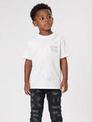 A young boy wearing a white short-sleeve t-shirt with a gray distressed graphic that reads 'WATER DEPT. SCHOOL OF DISCIPLINE' on the chest, paired with black patterned pants, against a light gray background.