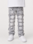 Light gray distressed denim jeans with large frayed patch pockets and ripped details, shown on a model wearing white sneakers against a light gray studio background.