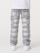 Light gray distressed denim jeans with large patch pockets and frayed cutout details, shown on a model from the back wearing white sneakers against a light gray studio background.