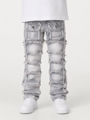 Light gray distressed denim jeans with heavy ripped patches and frayed edges, shown on a model from the waist down wearing white sneakers against a plain light background.