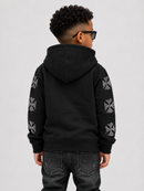 A child model shown from the back wearing a black pullover hoodie with silver geometric cross patterns down both sleeves, paired with dark jeans and black sunglasses, against a light gray background.