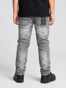 A person shown from the back wearing washed gray denim jeans with a black t-shirt and black sneakers, photographed against a light gray studio background.