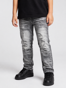 A person wearing distressed gray washed denim jeans with ripped details, paired with a black t-shirt and black platform sneakers, shown from the waist down on a light gray studio background.