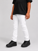 A person wearing white distressed skinny jeans with ripped knee details, paired with a black t-shirt and black sneakers, standing against a light gray studio background.
