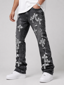 A person wearing dark gray distressed jeans with multiple white cross patches and ripped details, paired with a white t-shirt and white sneakers, photographed against a light gray studio background.
