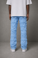 A person shown from the back wearing light blue frayed denim jeans, a white t-shirt, and white sneakers against a gray studio background.