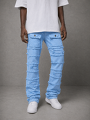 A person wearing light blue heavily distressed ripped jeans with layered frayed detailing, styled with a white t-shirt and white sneakers against a gray studio background.
