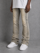 A person wearing beige distressed denim jeans with a dotted pattern, styled with a white t-shirt and white sneakers against a gray studio background.