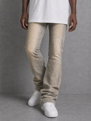 A person wearing beige textured skinny jeans with small metallic stud embellishments, styled with a white t-shirt and white sneakers against a gray studio background.