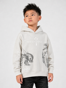 A young boy wearing a light gray hoodie with a black graphic print of a wolf and the text 'HOLY LAND' and '2001', paired with dark jeans, against a plain light gray background.