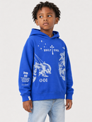 A young boy wearing a bright blue pullover hoodie with white graphic prints and light wash jeans, standing against a light gray studio background.