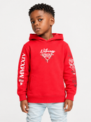 A young boy wearing a bright red hoodie with white graphic prints and text, paired with light blue jeans, standing against a light gray studio background.
