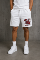 White athletic drawstring shorts with a red and black 'ATHLETIC 4M DEPARTMENT' graphic on the left leg, worn by a model with white sneakers and socks against a gray concrete wall. By Fresh N Fitted 
