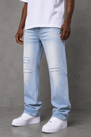 A person wearing light-wash distressed jeans with ripped knee details, paired with a white t-shirt and white platform sneakers, standing against a textured gray concrete wall. By Fresh N Fitted.