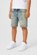 A child wearing light-wash blue distressed denim shorts with frayed hems, paired with a white t-shirt and white sneakers, shown from the waist down on a light gray studio background.
