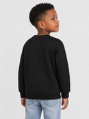 A young boy with short dark hair is shown from the back wearing a solid black crewneck sweatshirt and light blue jeans, standing against a light gray studio background.